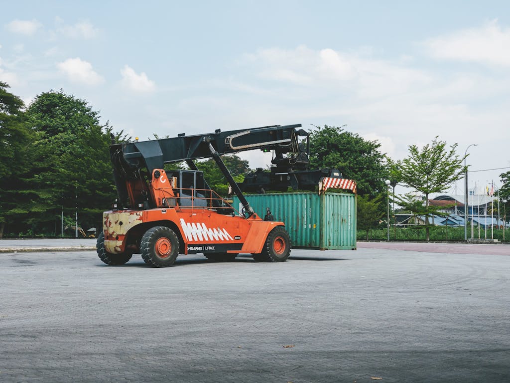 A container handler lifts a cargo container at an outdoor industrial port in Ipoh, Malaysia.