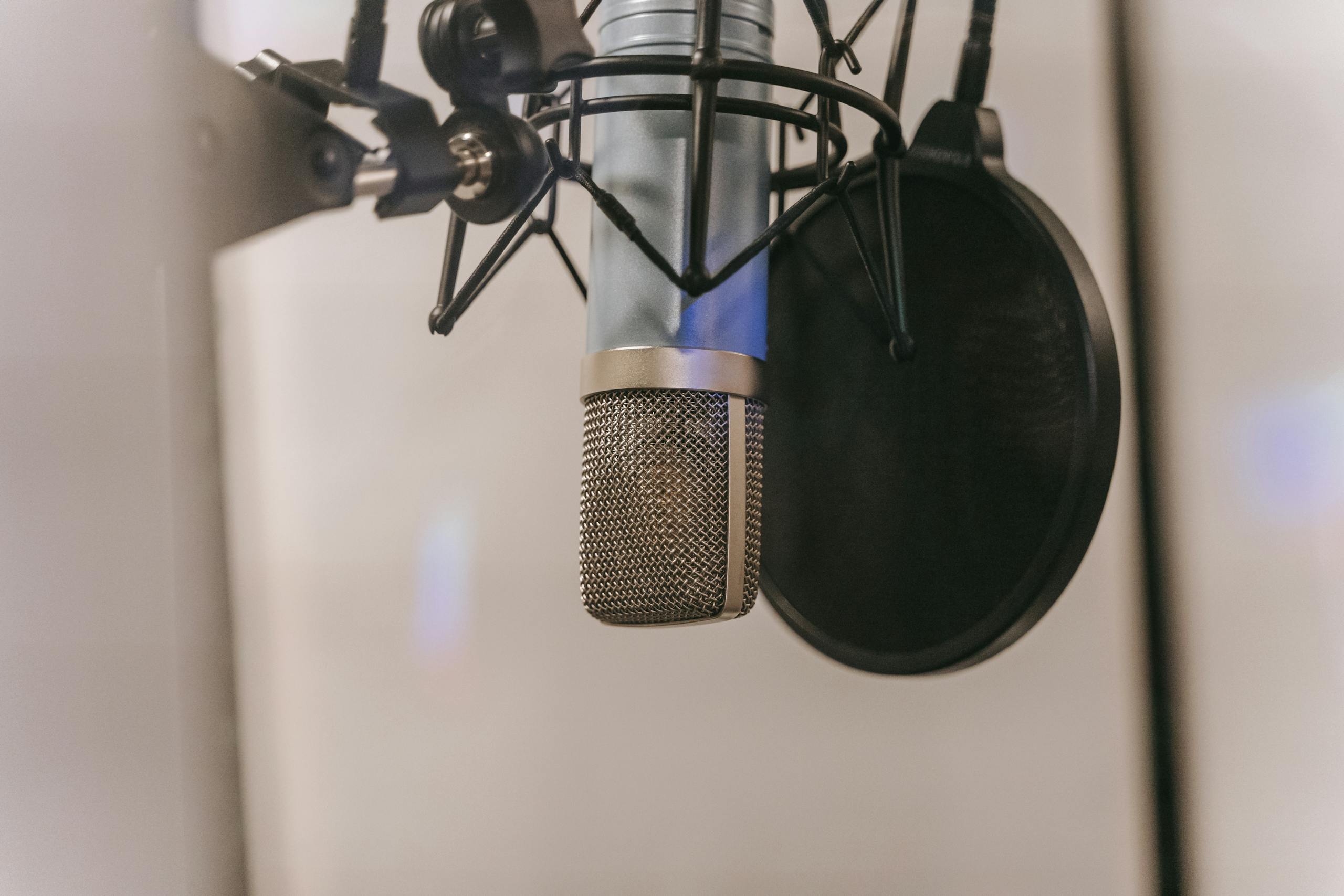 Close-up of a condenser microphone with pop filter in a studio setting, ideal for audio and podcasting.