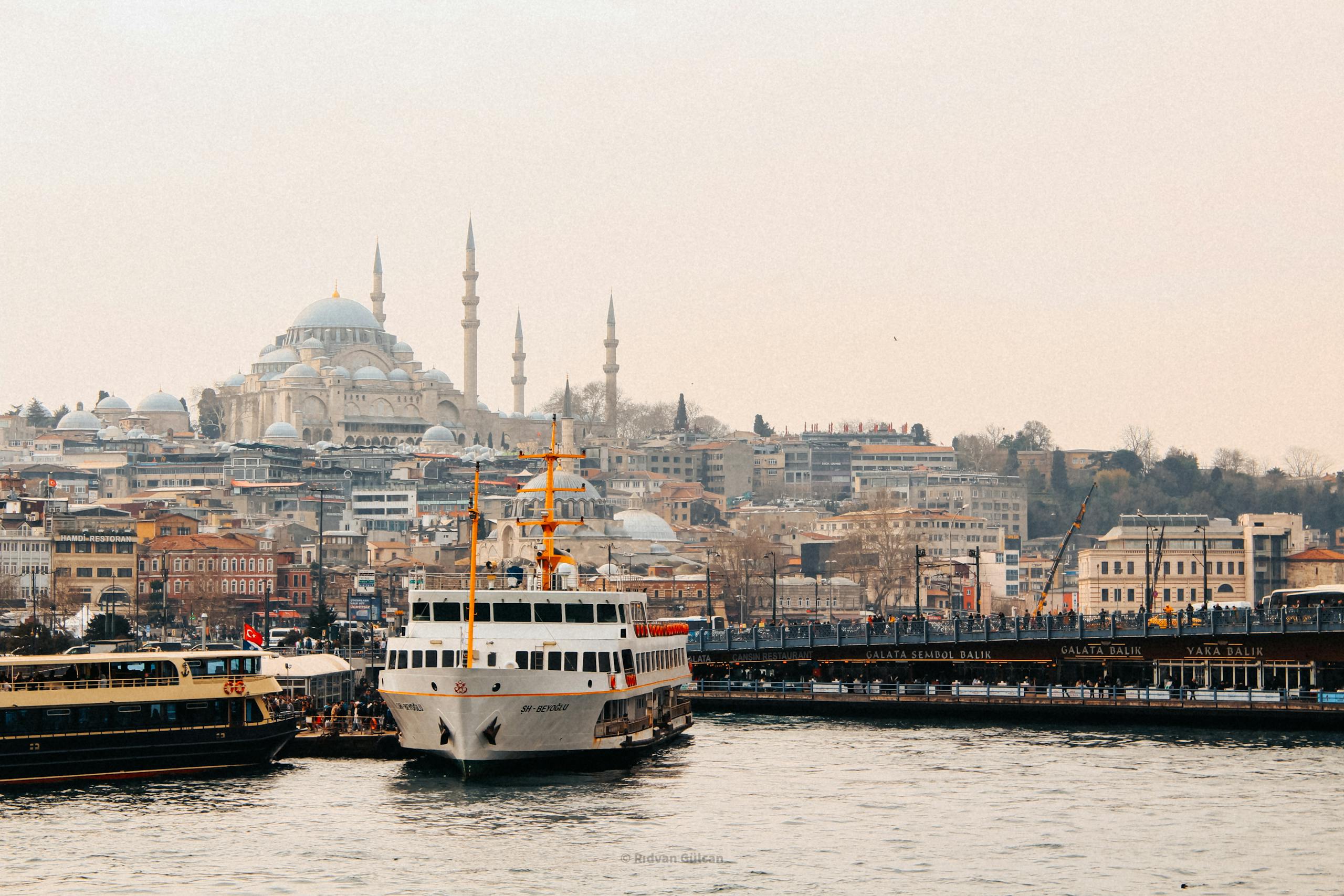 Scenic view of Istanbul skyline with ferries on the Bosphorus and Suleymaniye Mosque in the background.